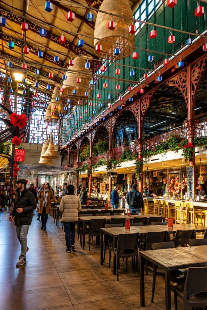 Historic Mercato Centrale food hall with iron arches, hanging lights, tables, and market stalls
