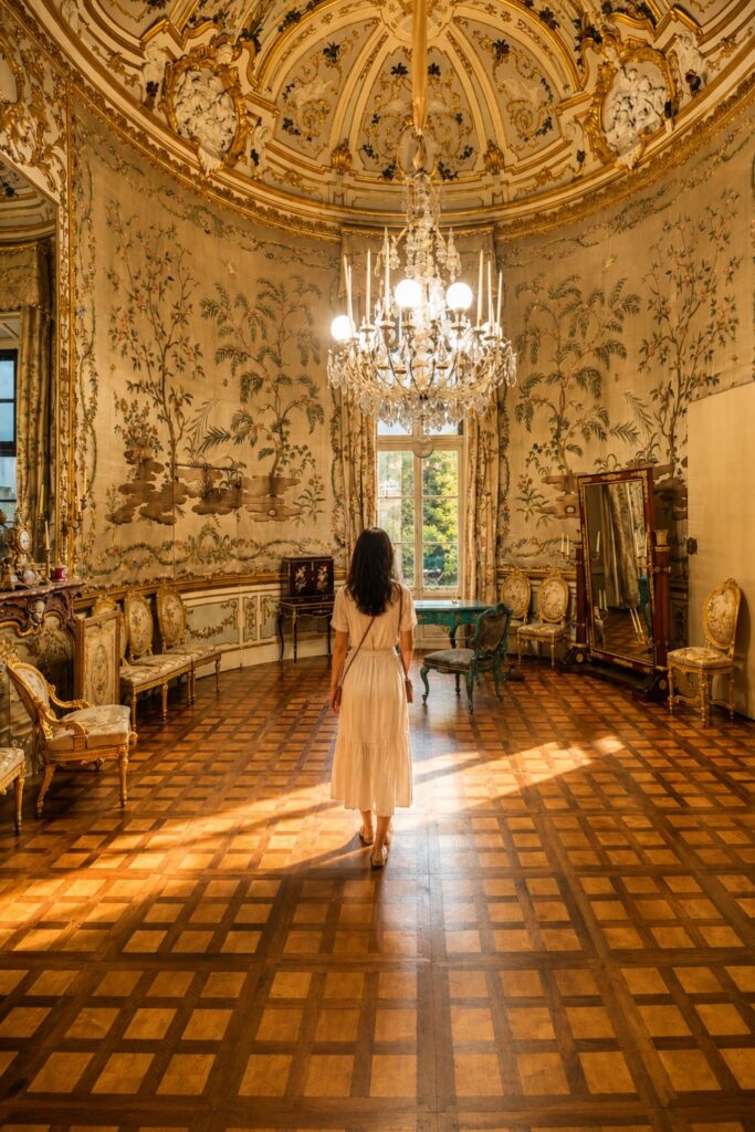 Ornate Palazzo Pitti salon with gilded ceiling, painted walls, chandelier, and parquet floor