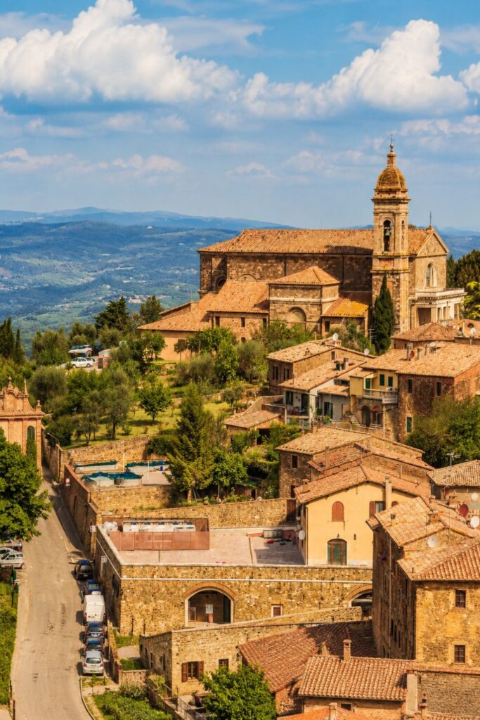 Terracotta rooftops and stone church in Montalcino with rolling Tuscan hills beyond
