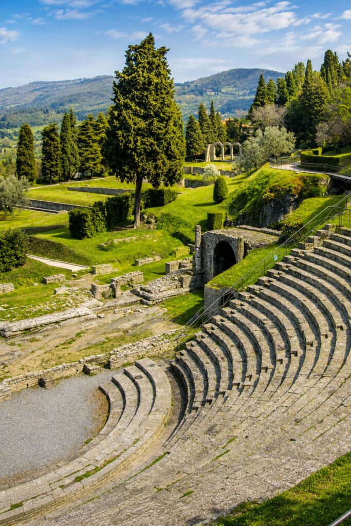 Fiesole’s ancient Roman theater curves through green lawns beneath wooded Tuscan hills.