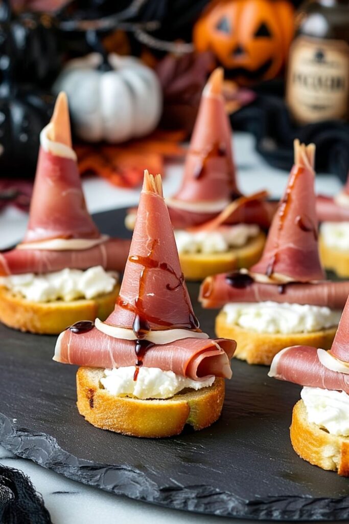 Toasted crostini topped with whipped feta and prosciutto folded into pointy witch hats.