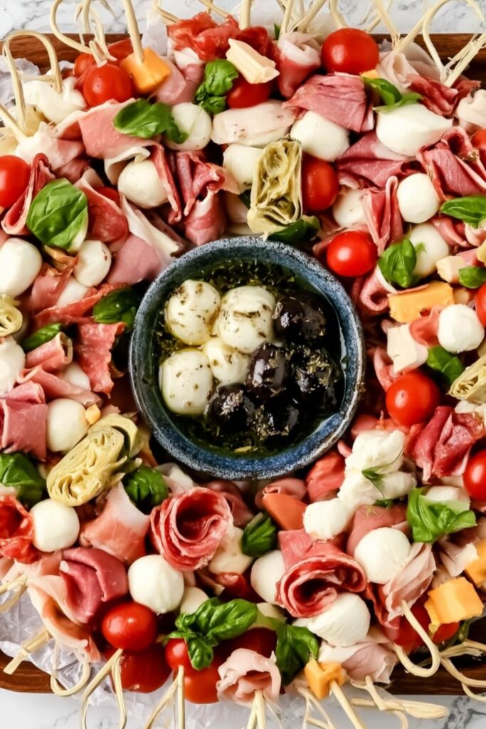 Skewers of cured meats, cheese, tomatoes, and basil arranged into a festive wreath shape.