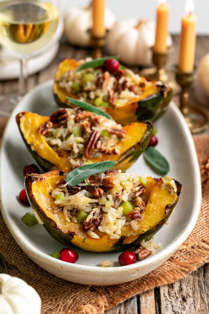 Roasted acorn squash quarters filled with seasoned rice and toasted pecans on a platter.