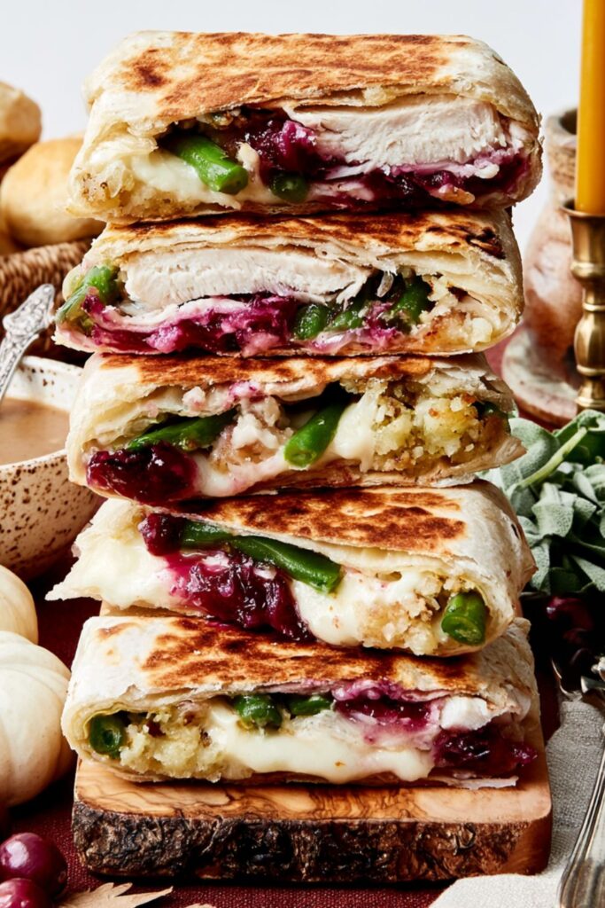 Stacked tortilla crunchwraps cut in half showing layered turkey, green beans, and melted cheese.